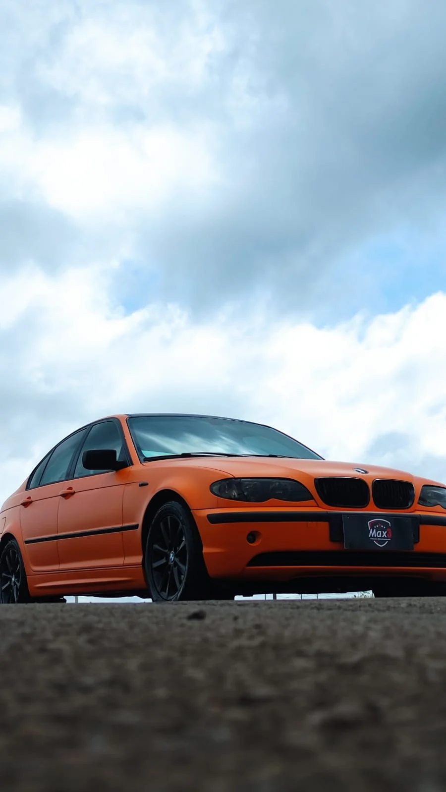 BMW laranja em um ângulo baixo, com a placa Max 3