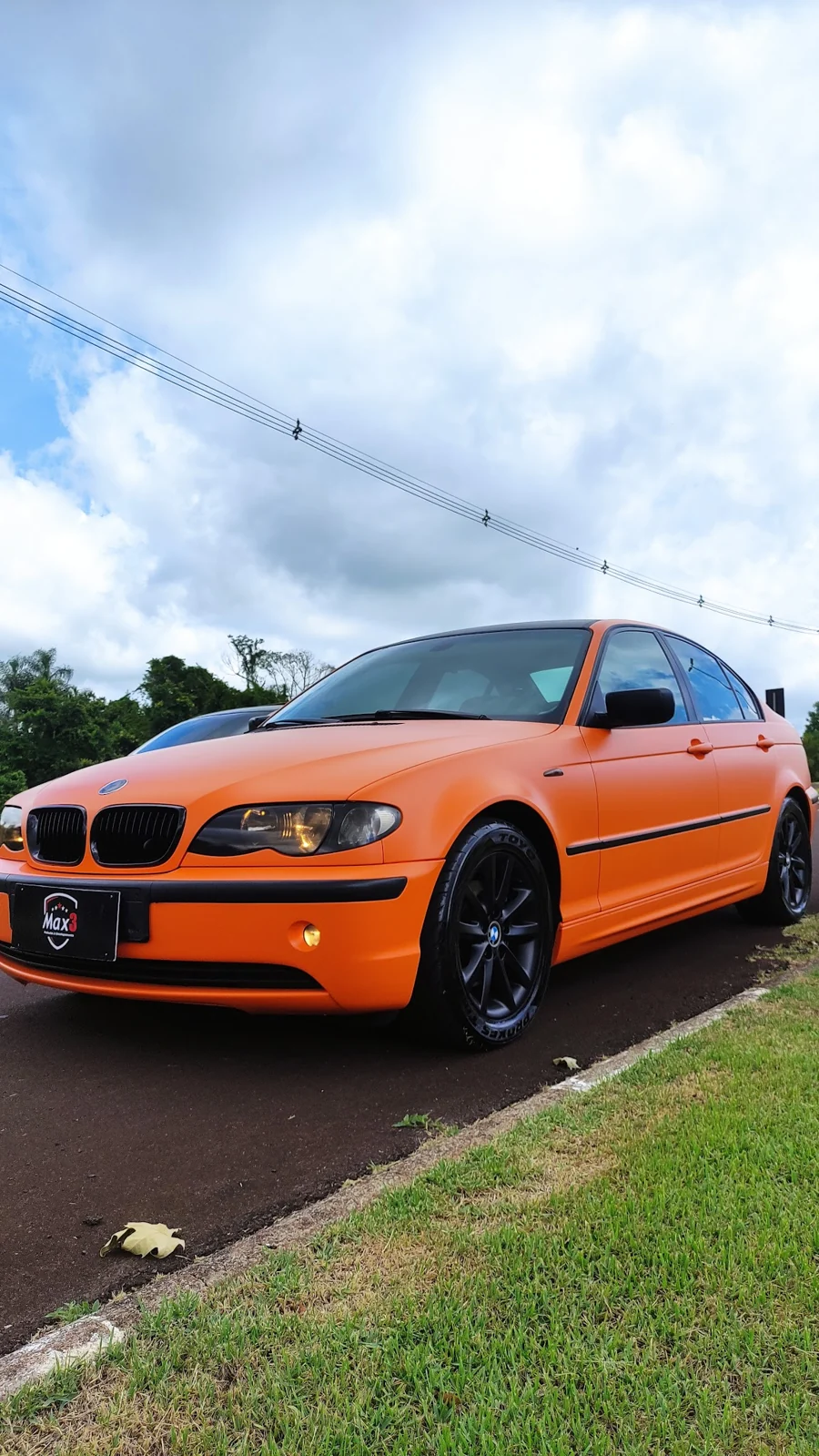 BMW laranja com identificação da Max 3, fotografado ao ar livre